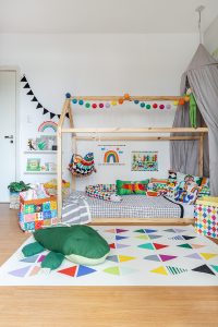 quarto infantil com cama casinha e tapete estampado colorido