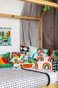 cama infantil com colcha matelassada e almofadas coloridas