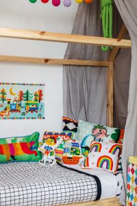cama infantil com colcha matelassada e almofadas estampadas