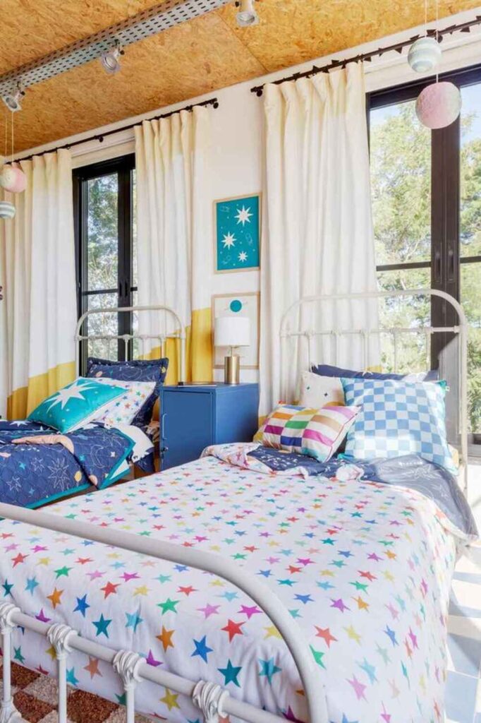 Quarto infantil com parede de planetas coloridos e roupa de cama arco-íris, decoração temática espacial cheia de cores e imaginação.