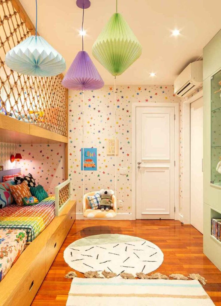 Quarto infantil decorado com papel de parede de estrelas coloridas, luminárias em tons pastéis e cama com roupas de cama estampadas, ambiente alegre e lúdico.
