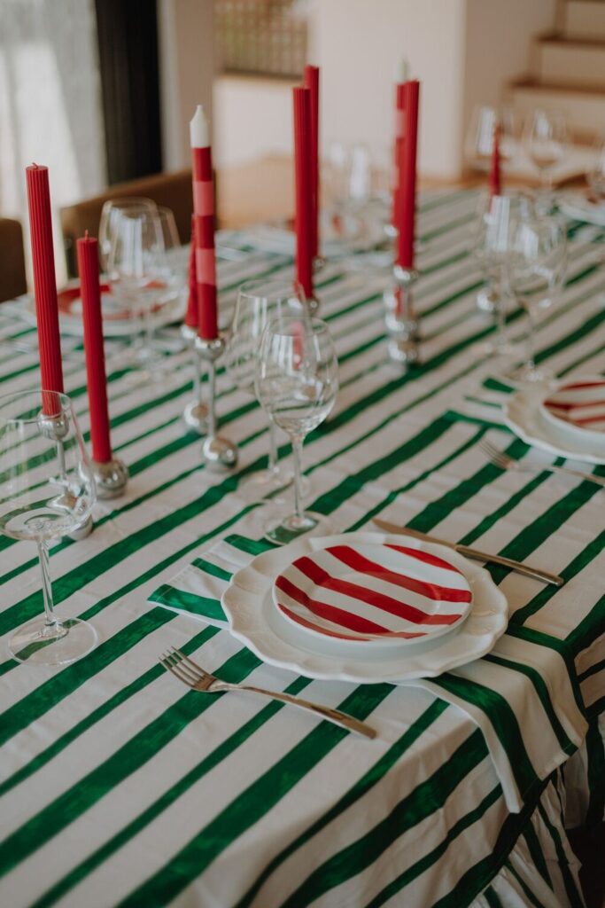 Mesa de natal decorada com velas vermelhas, taças, pratos e talheres