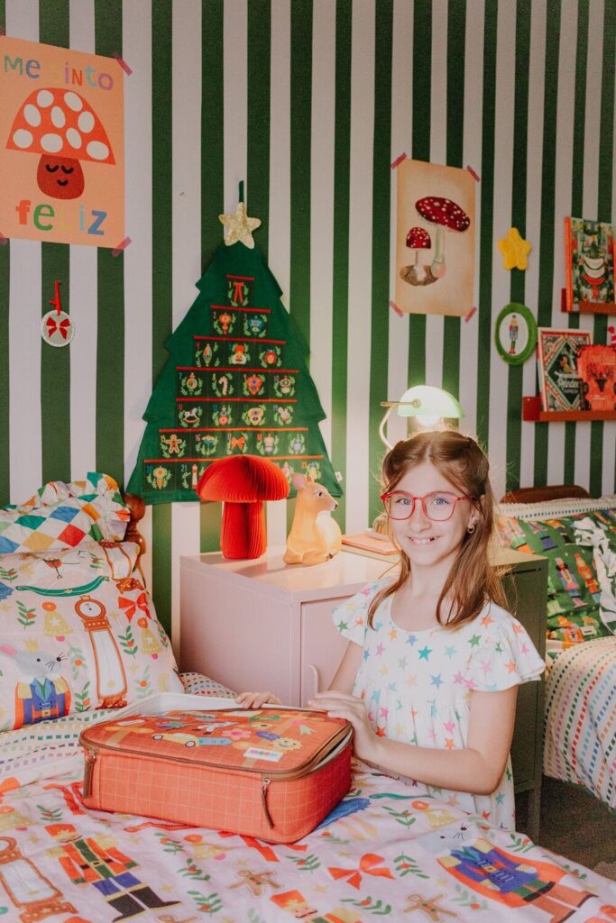 Menina em quarto temático de natal fechando uma mochila