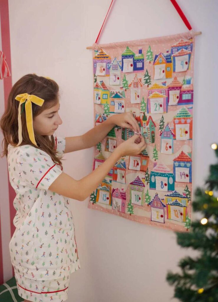Quarto infantil com paredes listradas em vermelho e decoração de Natal com calendário do Advento pendurado.
