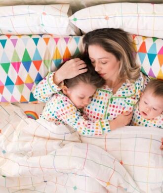 Mãe fazendo cama compartilhada com dois bebês