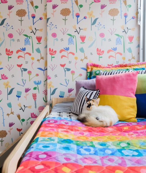 Quarto infantil feminino decorado com rosa, branco e cores diversas. Gato em cima da cama