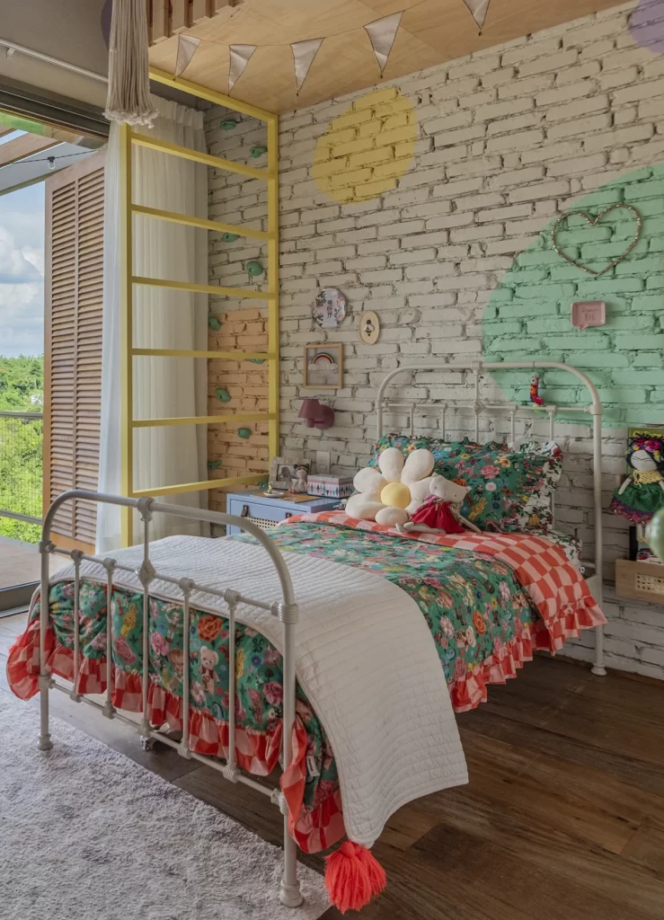 Cama de ferro branca em quarto infantil colorido com parede de tijolinhos pintados.