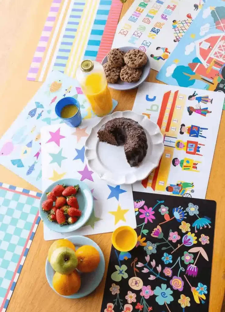 Mesa de café da manhã divertida para crianças na cozinha, com frutas, bolo, suco e jogos educativos coloridos.