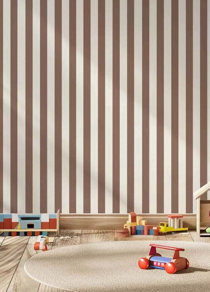 Parede com papel de parede listrado em tons neutros e brinquedos de madeira no chão