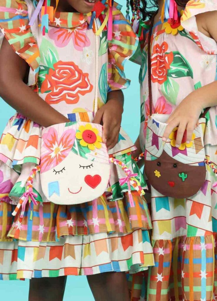 Vestidos infantis estampados com bolsas artesanais coloridas para composição de traje junino.