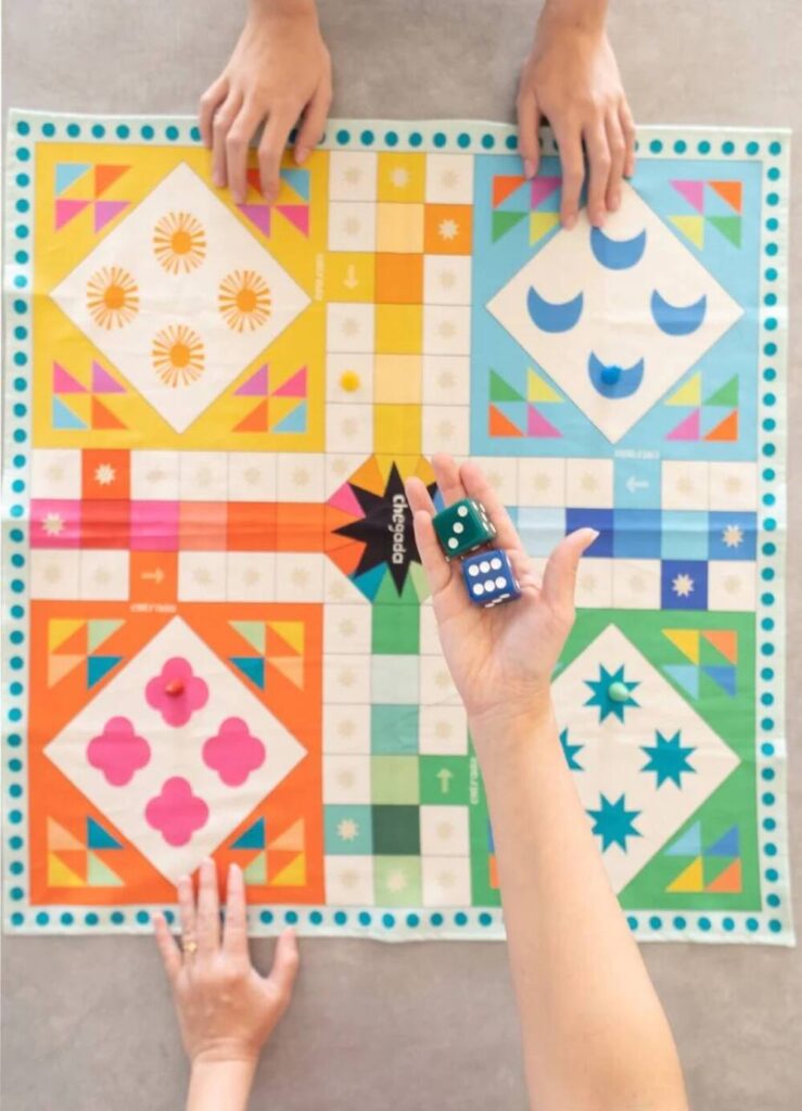 Crianças jogando tabuleiro colorido de brincadeiras educativas para estimular raciocínio lógico e interação.