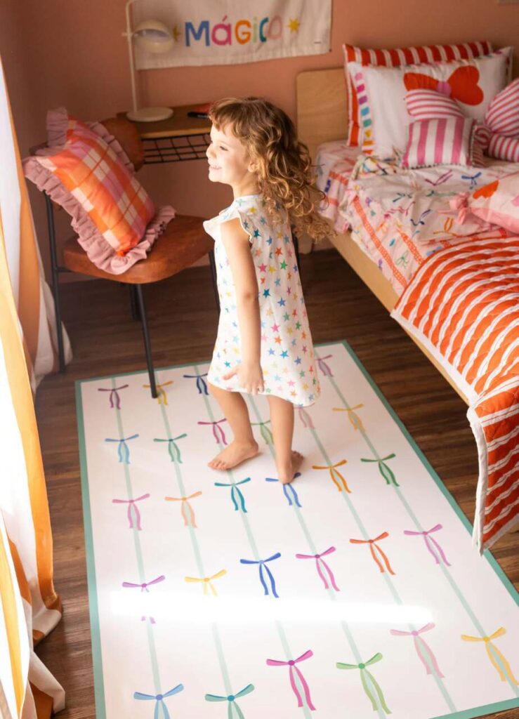 Quarto de irmãos com decoração infantil colorida, tapete lúdico e cama compartilhada para crianças.
