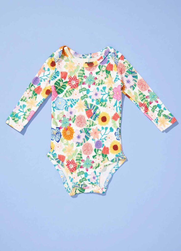Body infantil de manga longa com estampa floral colorida, ideal para quem pesquisa o que levar na bolsa da maternidade.