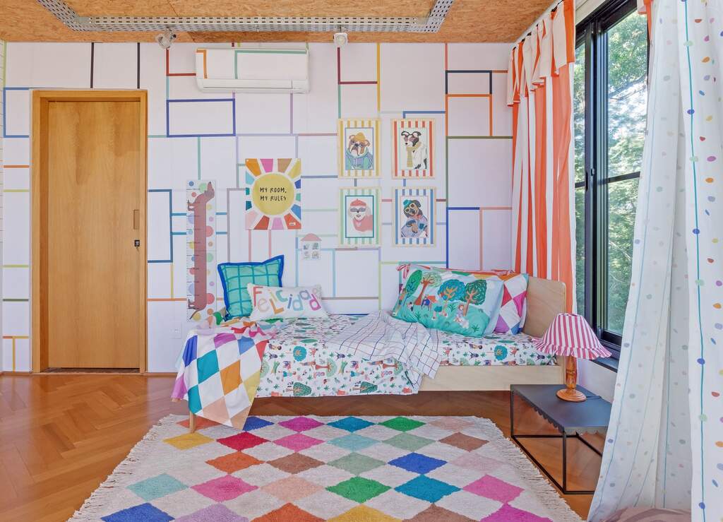 Quarto infantil decorado com roupa de cama estampada de cachorrinhos, almofadas coloridas e decoração divertida.