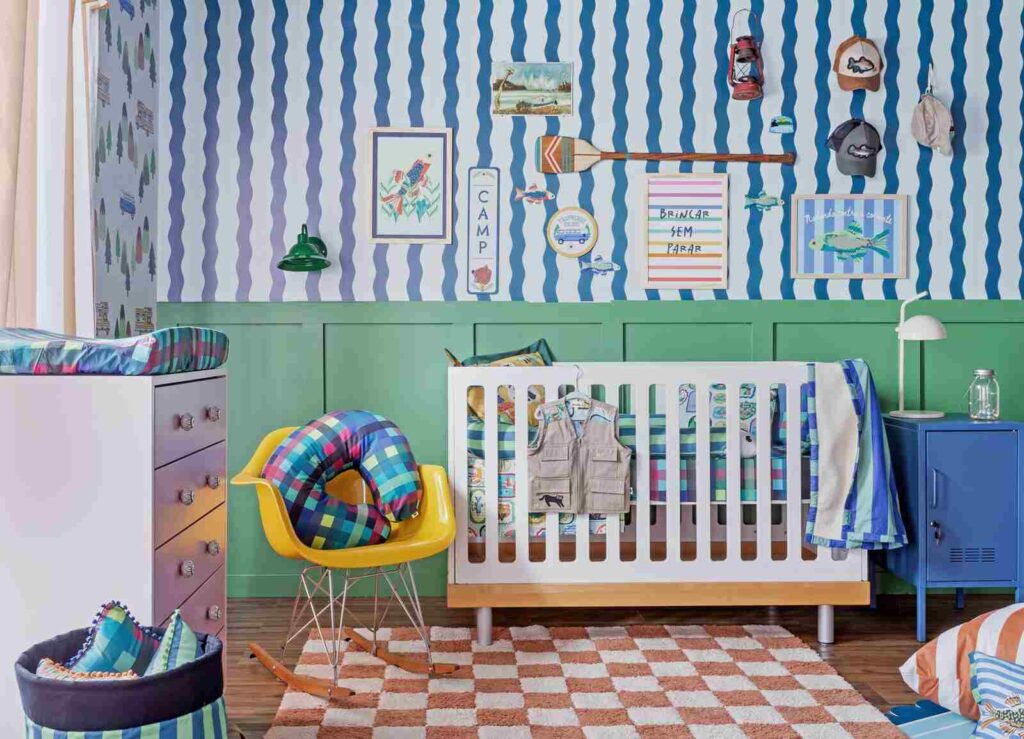Quarto de bebê masculino com tapete estampado, berço branco, papel de parede listrado e decoração inspirada em aventura.